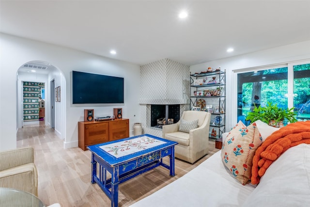 living area featuring arched walkways, recessed lighting, light wood finished floors, and a multi sided fireplace