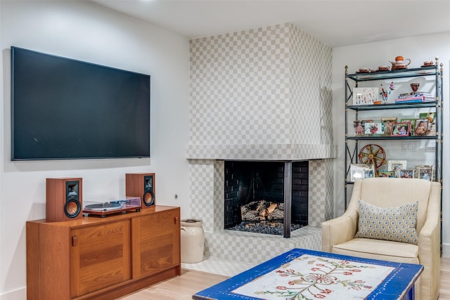 living area featuring a tile fireplace and light wood-type flooring