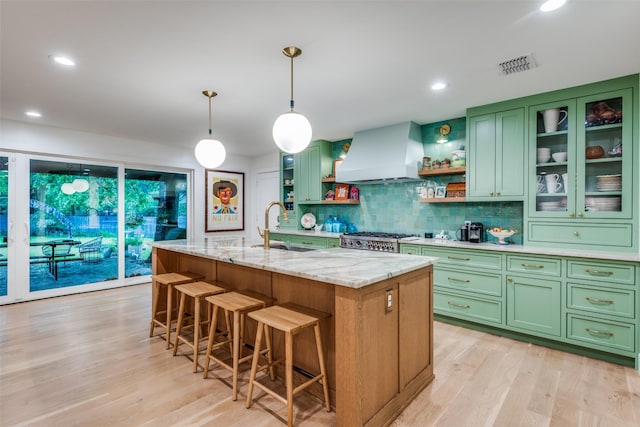 kitchen featuring green cabinets, premium range hood, a sink, open shelves, and light wood-type flooring