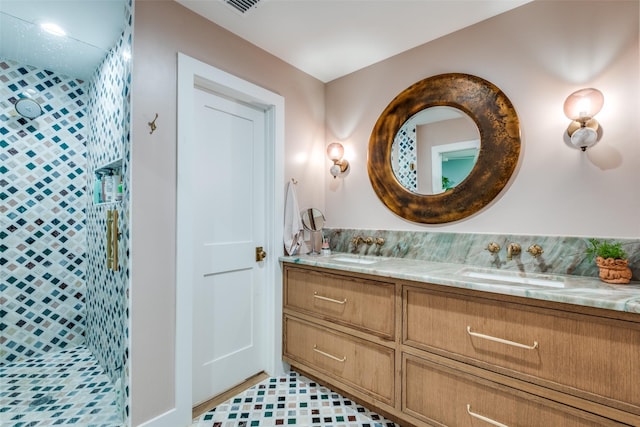 full bathroom with tiled shower and double vanity