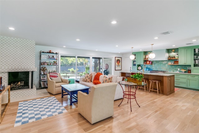 living area featuring light wood-style flooring, a tile fireplace, and recessed lighting