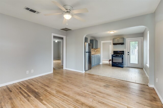 2524 Malvern Trl, Fort Worth, TX 76105 - unfurnished living room featuring arched walkways, light wood-type flooring, ceiling fan, and baseboards