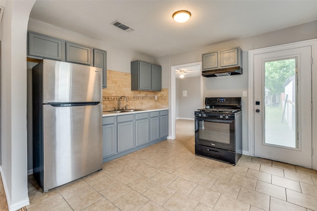 2524 Malvern Trl, Fort Worth, TX 76105 - kitchen featuring freestanding refrigerator, black gas range, a sink, under cabinet range hood, and tasteful backsplash