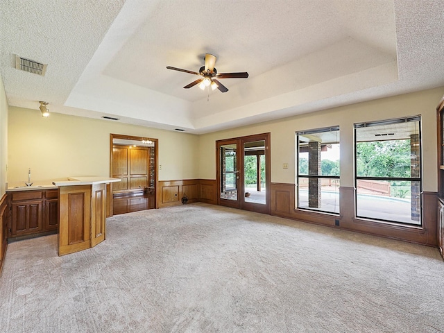 302 Fairway Ct, Willow Park, TX 76087 - unfurnished living room with a tray ceiling, light carpet, a ceiling fan, a sink, and wainscoting