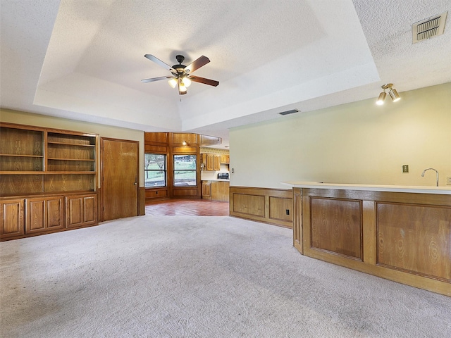 302 Fairway Ct, Willow Park, TX 76087 - unfurnished living room with a tray ceiling, a textured ceiling, a ceiling fan, light carpet, and wainscoting