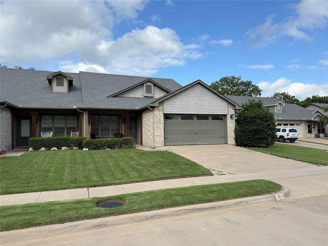 view of front of house with a garage, driveway, roof with shingles, and a front yard