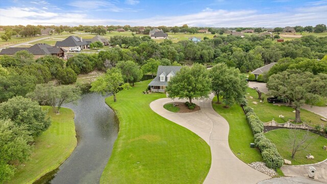 aerial perspective of suburban area featuring a nearby body of water and a tree filled landscape