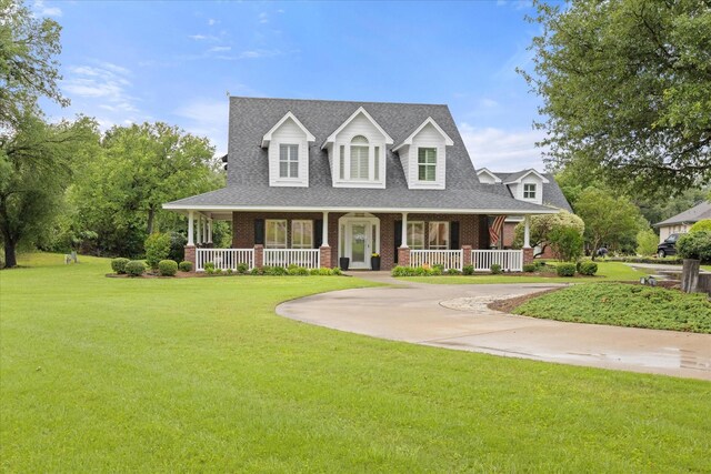 view of front of property with a porch, brick siding, a front yard, and a shingled roof