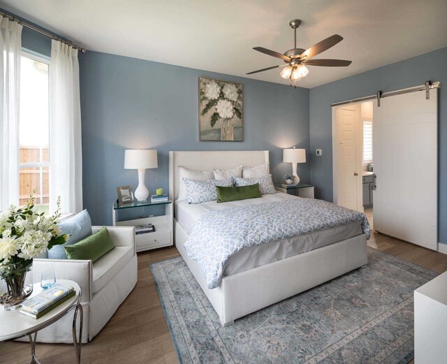 2210 Desmond Dr, Forney, TX 75126 - bedroom with a barn door, wood finished floors, and a ceiling fan