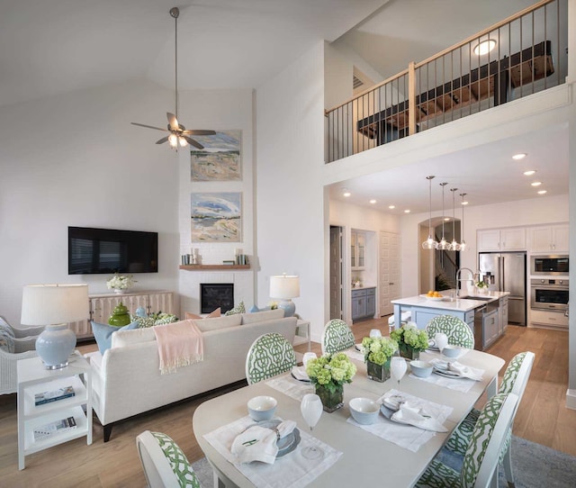2210 Desmond Dr, Forney, TX 75126 - dining room featuring high vaulted ceiling, a fireplace, light wood-style floors, ceiling fan, and a chandelier