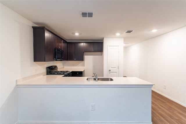 2923 Cascade Ln, Forney, TX 75126 - kitchen with black microwave, a sink, range with gas cooktop, a peninsula, and dark brown cabinetry