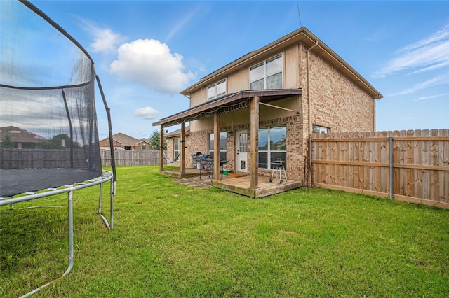 back of property featuring a trampoline and brick siding