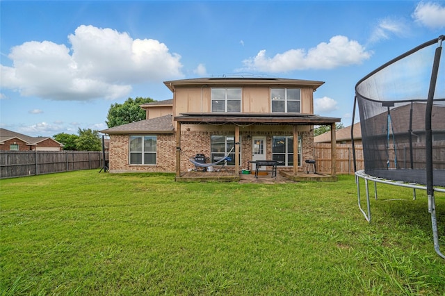 back of property with a trampoline, a patio area, roof mounted solar panels, and brick siding