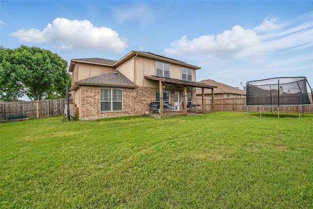 back of property featuring a trampoline, a patio area, brick siding, and roof with shingles