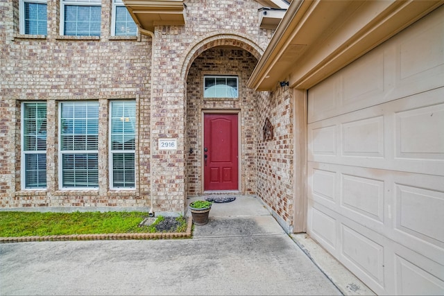 property entrance with brick siding and an attached garage