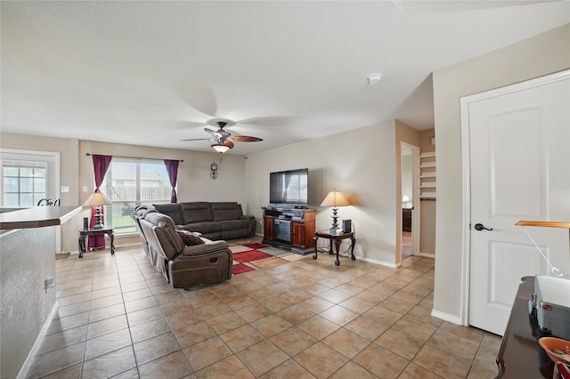 living area with ceiling fan, baseboards, and light tile patterned flooring