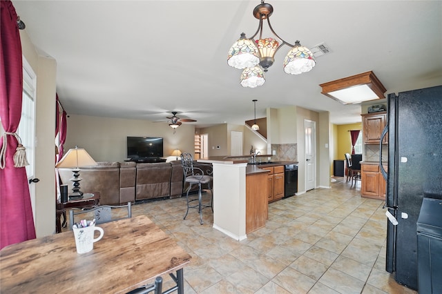 kitchen featuring a peninsula, black appliances, a sink, a breakfast bar area, and open floor plan