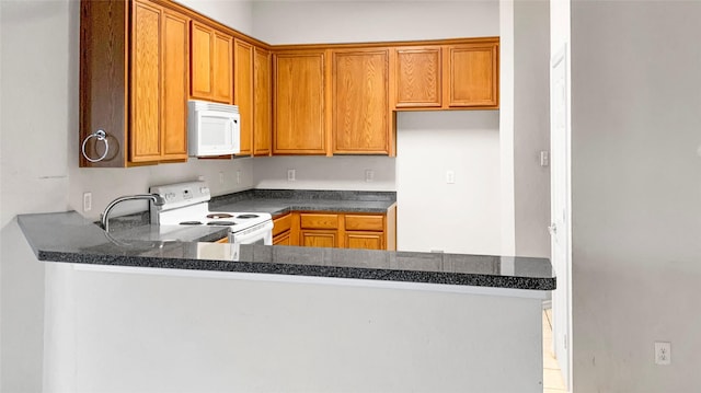 kitchen featuring white appliances, brown cabinets, a peninsula, and a sink