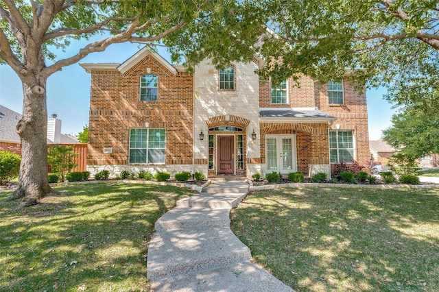 traditional-style house with french doors, brick siding, and a front lawn