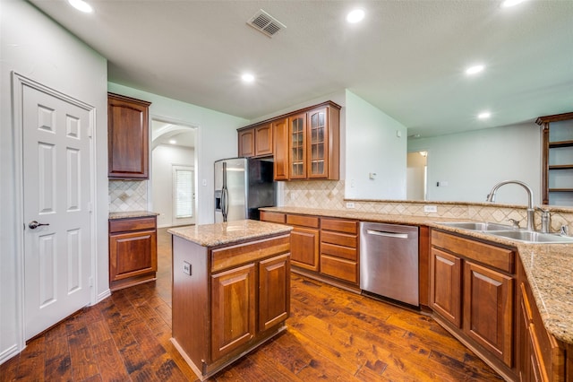 kitchen with stainless steel appliances, a sink, backsplash, glass insert cabinets, and recessed lighting