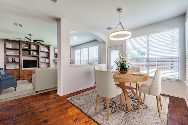 dining space with baseboards, hardwood / wood-style floors, a ceiling fan, and arched walkways