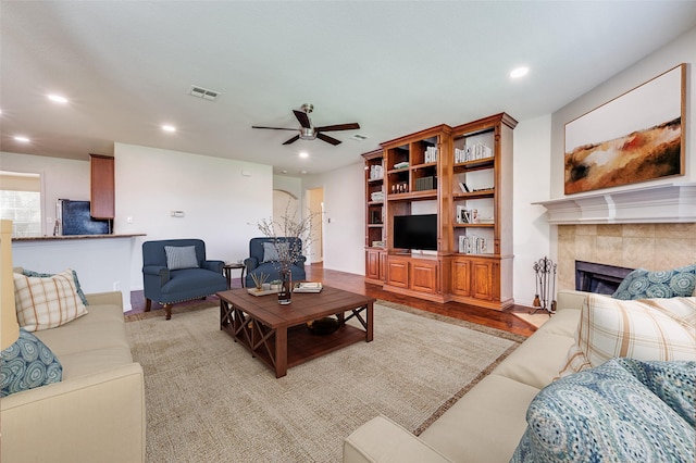 living room featuring a ceiling fan, a tile fireplace, recessed lighting, and light wood finished floors