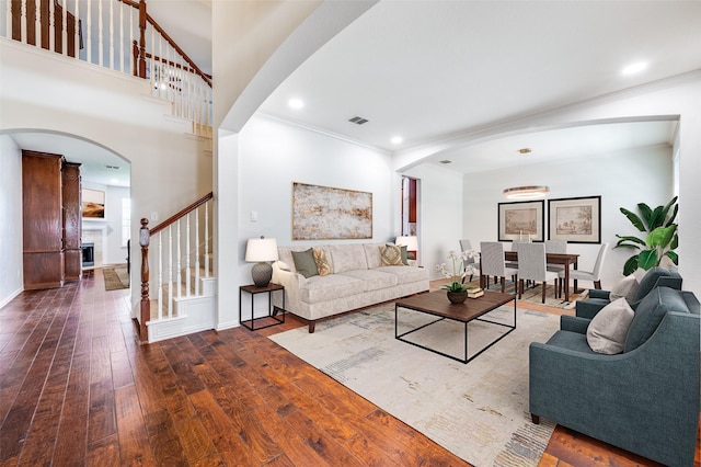 living room with stairway, arched walkways, hardwood / wood-style flooring, crown molding, and recessed lighting