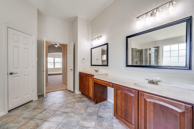 full bathroom featuring a tile shower, double vanity, and baseboards