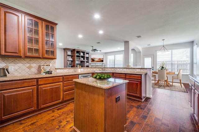 kitchen with a sink, a peninsula, dark wood finished floors, backsplash, and recessed lighting