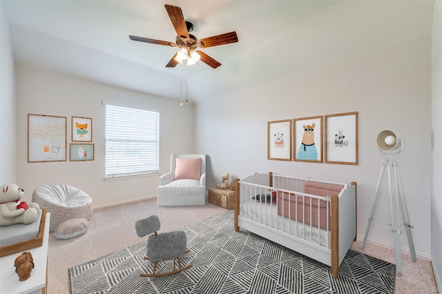 bedroom with baseboards, carpet, a crib, and ceiling fan