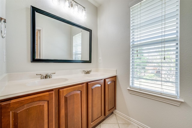 bathroom with double vanity, tile patterned floors, a textured wall, and baseboards