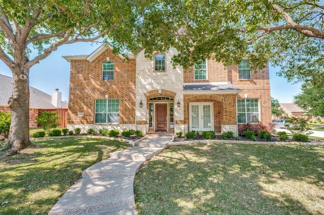 view of front of house with french doors, brick siding, and a front yard