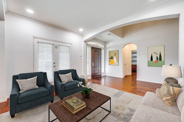 living room featuring arched walkways, crown molding, wood finished floors, baseboards, and recessed lighting