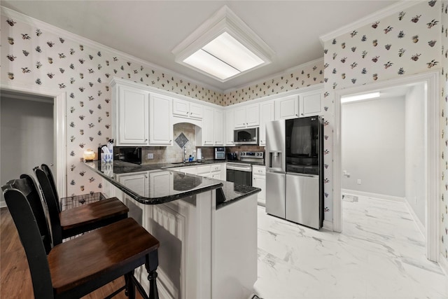 209 Village Cir, Waco, TX 76710 - kitchen with stainless steel appliances, crown molding, a peninsula, white cabinets, and wallpapered walls