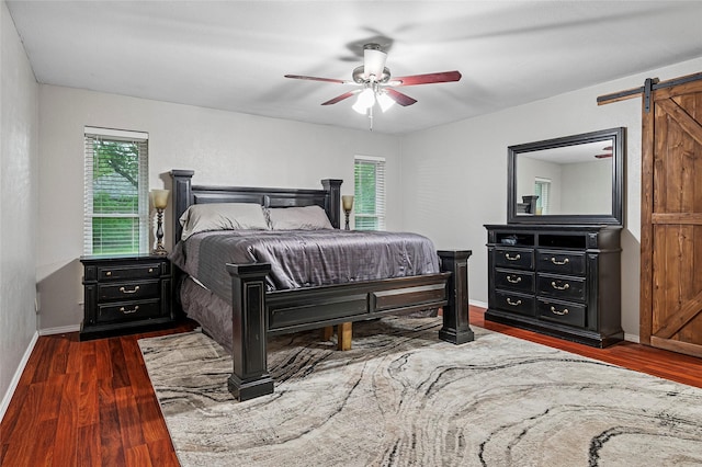 bedroom featuring a barn door, wood finished floors, baseboards, and ceiling fan