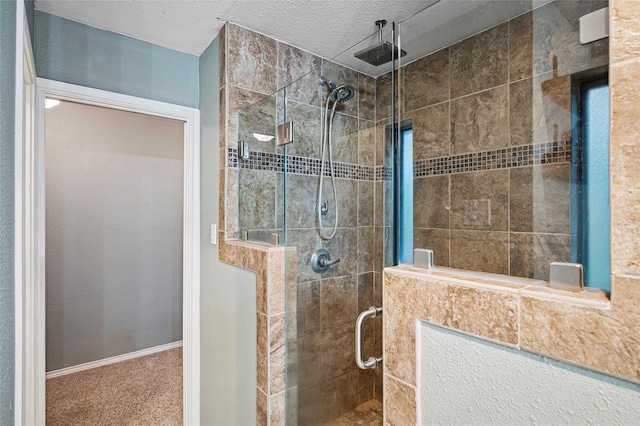 bathroom featuring a stall shower, a textured ceiling, and baseboards