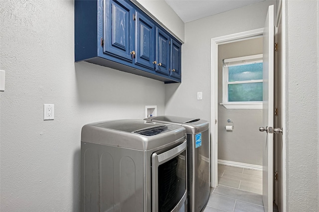 laundry area with washing machine and clothes dryer, cabinet space, light tile patterned flooring, and baseboards