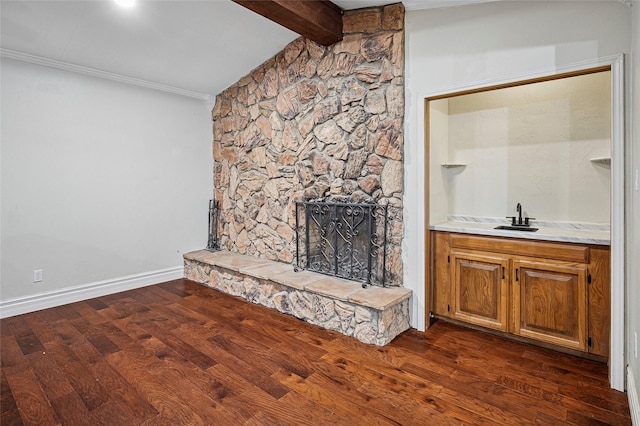 unfurnished living room featuring ornamental molding, dark wood finished floors, a fireplace, wet bar, and baseboards