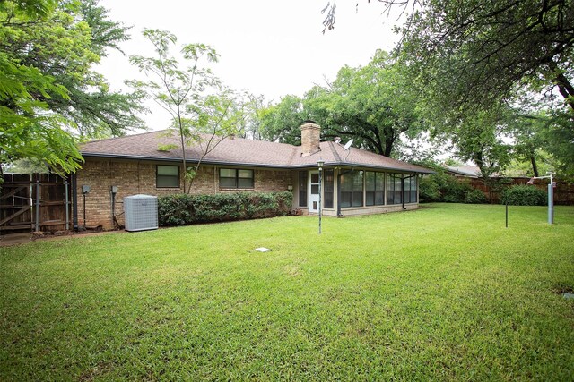 1305 Cliff Dr, Graham, TX 76450 - rear view of house with central air condition unit, a sunroom, a chimney, brick siding, and a shingled roof