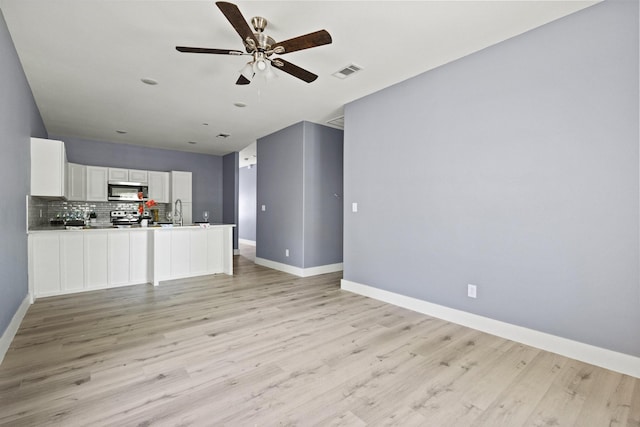 620 S First St, Sherman, TX 75090 - unfurnished living room featuring a ceiling fan, light wood-style flooring, baseboards, and a sink
