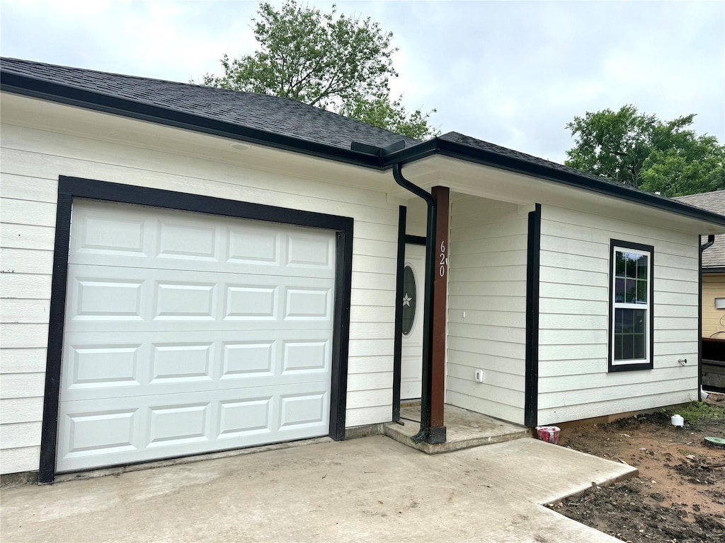 view of front facade with concrete driveway, a shingled roof, and an attached garage