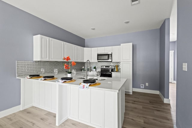 620 S First St, Sherman, TX 75090 - kitchen with stainless steel appliances, a sink, a peninsula, light wood-style flooring, and tasteful backsplash