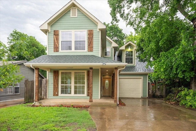 traditional home featuring a porch, a shingled roof, concrete driveway, an attached garage, and fence