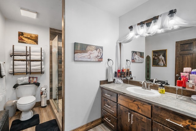 bathroom with wood finished floors, toilet, a shower stall, and vanity