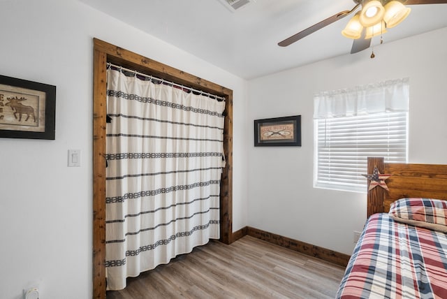 bedroom with wood finished floors, baseboards, and a ceiling fan