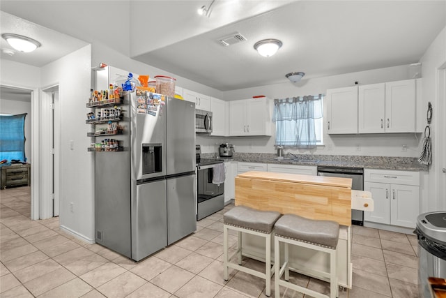 420 Whitney Ct, Rio Vista, TX 76093 - kitchen featuring stainless steel appliances, white cabinetry, a sink, light stone counters, and light tile patterned floors