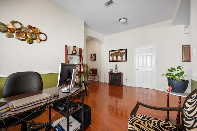 office featuring arched walkways and wood finished floors