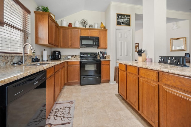 kitchen featuring black appliances, a sink, light stone counters, brown cabinetry, and vaulted ceiling