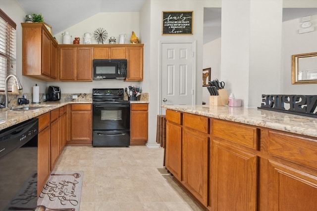 kitchen featuring black appliances, a sink, light stone countertops, brown cabinetry, and vaulted ceiling