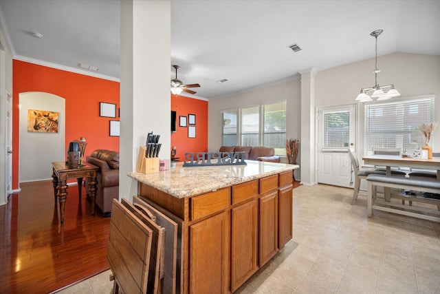 kitchen featuring a ceiling fan, light stone countertops, decorative light fixtures, open floor plan, and brown cabinets